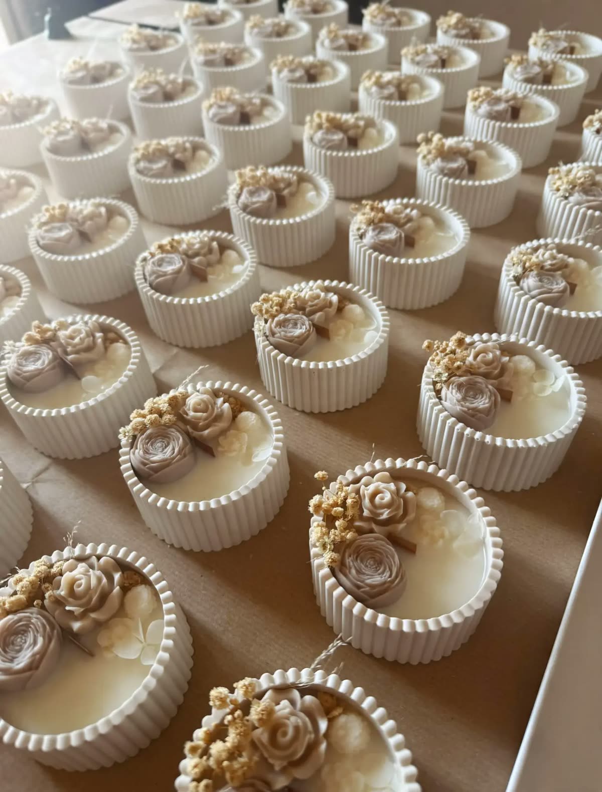 Candele rotonde in cera con rose e fiori secchi allineate in laboratorio