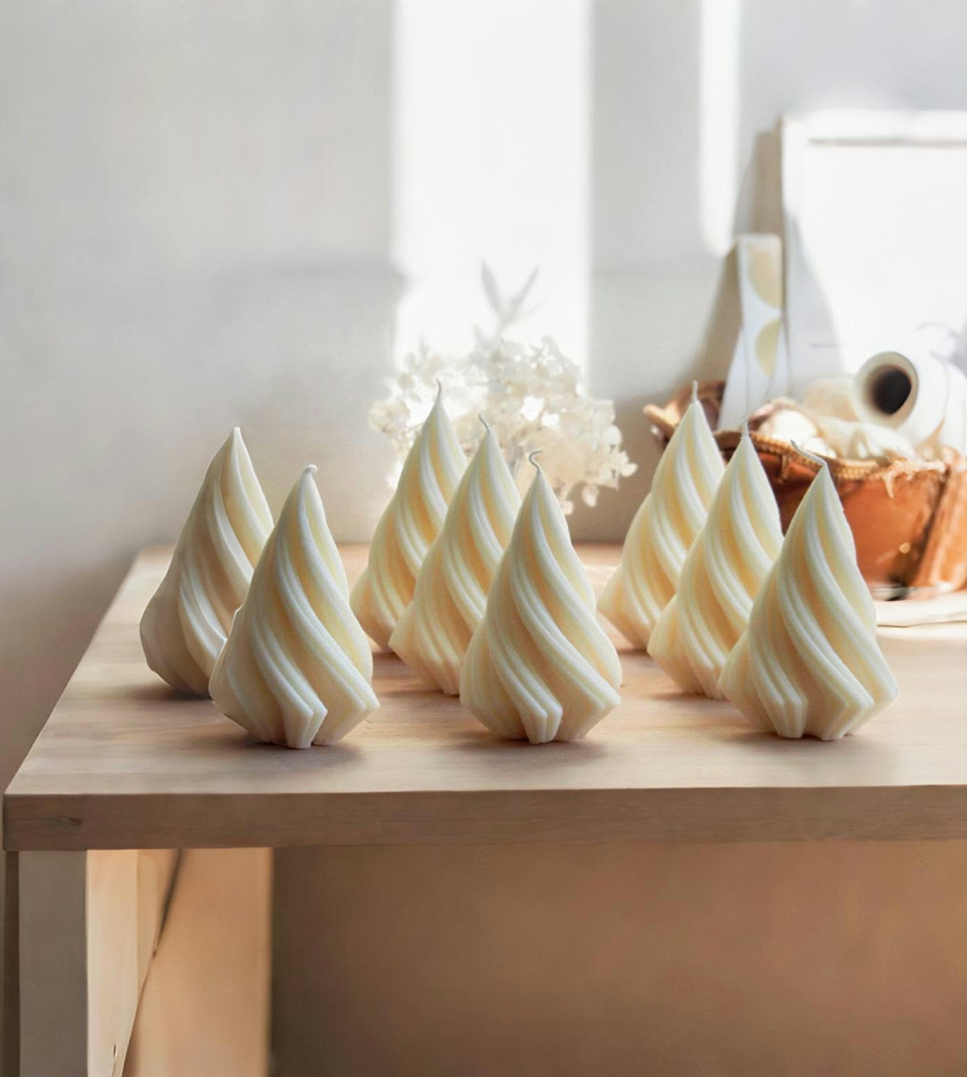 Candele natalizie a spirale in cera avorio allineate su un tavolo in legno